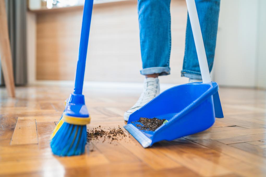 broom sweeping dust from floor