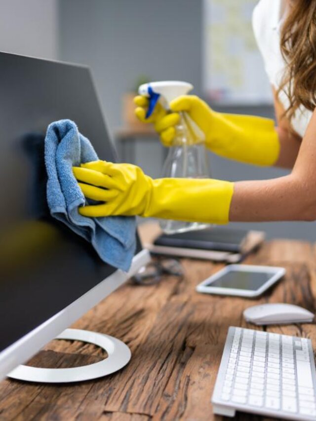 woman cleaning monitor on computer desk