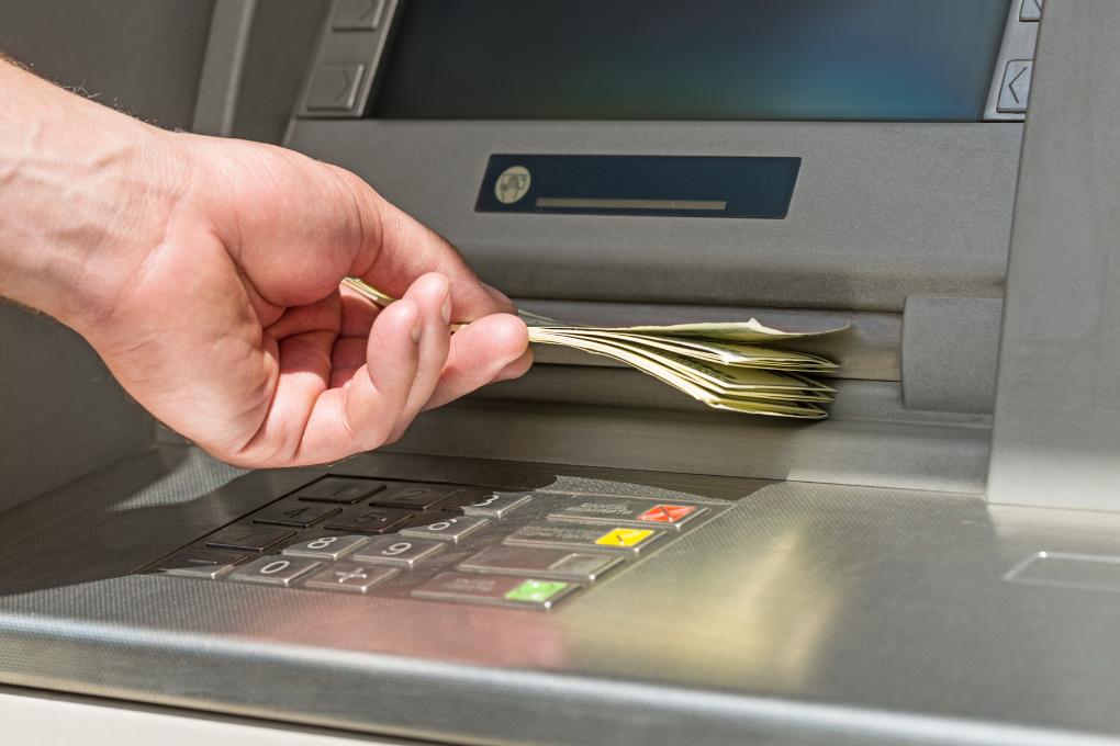 close up of hand touching money at ATM