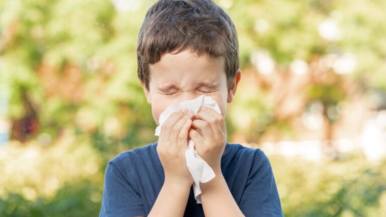 boy-sneezing-on-a-paper-towel-outside