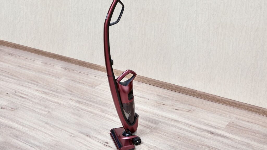 upright vaccum cleaner on a wood tile floor standing next to a wall